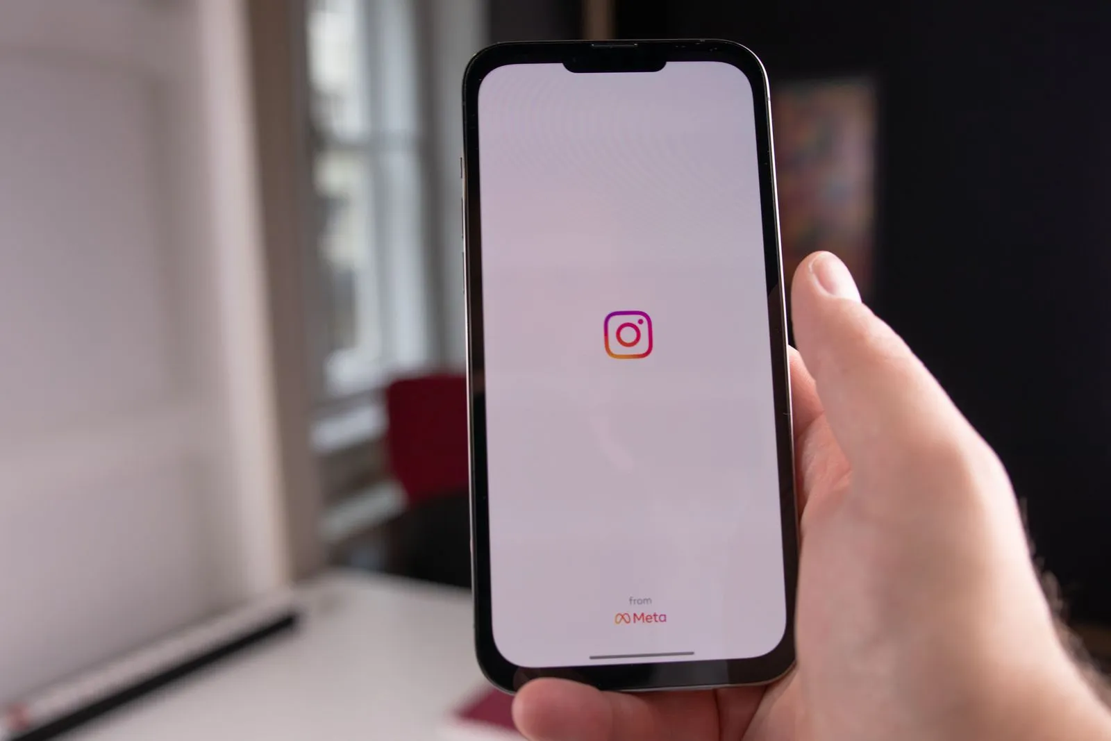 Una mano tiene uno smartphone che mostra la schermata iniziale dell'app Instagram