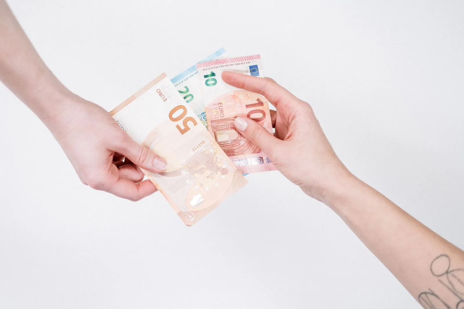 Due mani si scambiano banconote in euro su uno sfondo bianco