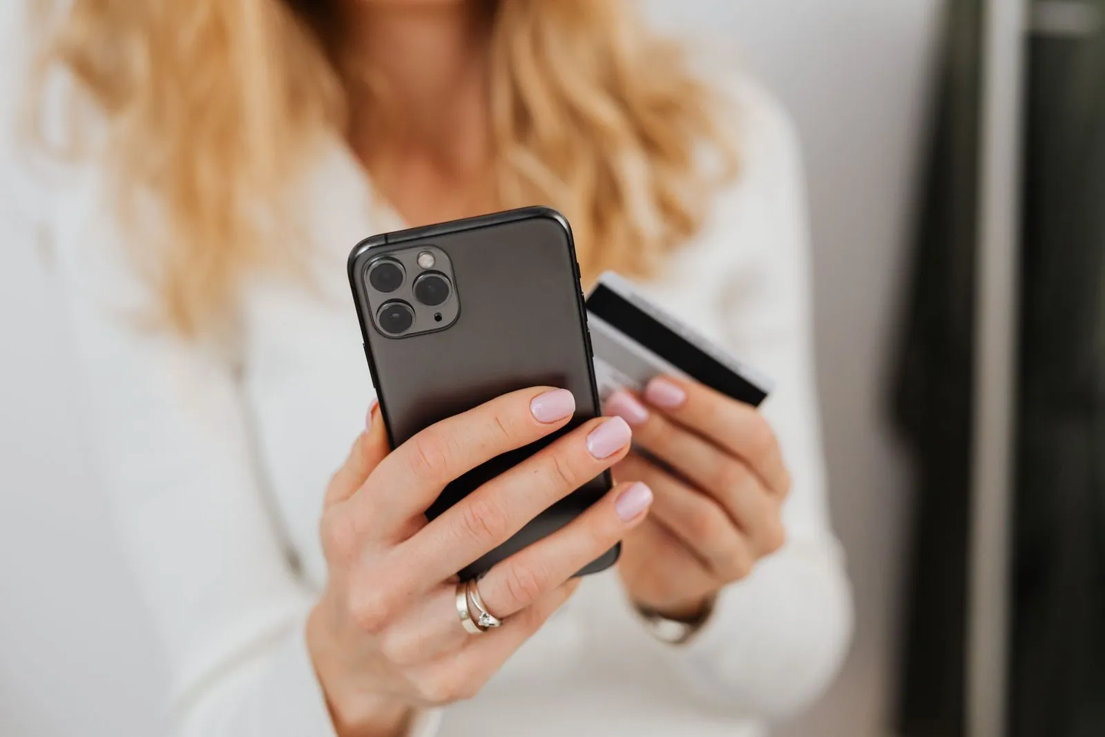 Mains tenant un smartphone et une carte bancaire pour payer en ligne
