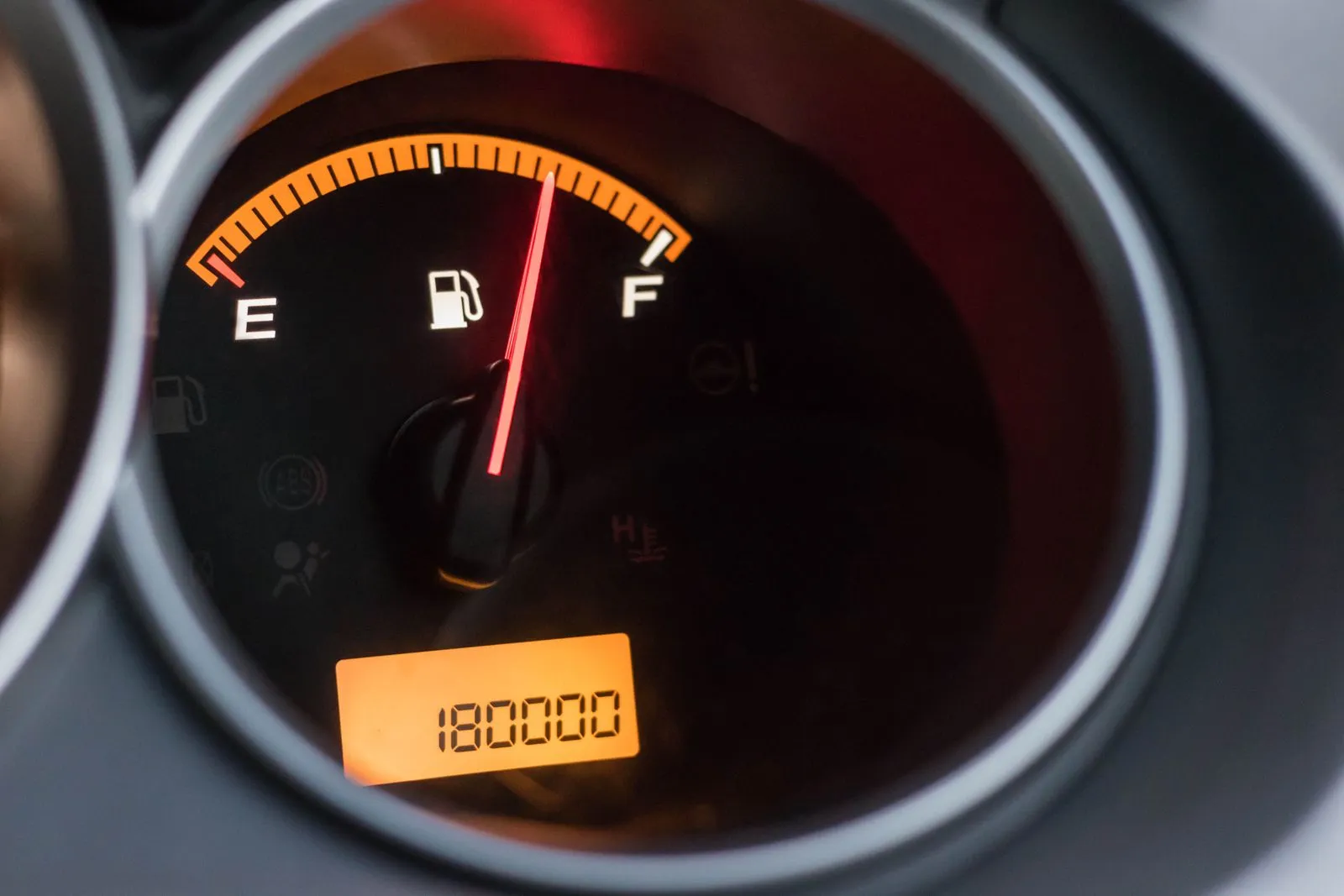 Indicatore del carburante di un'auto con la lancetta tra metà e pieno, sotto il display del contachilometri
