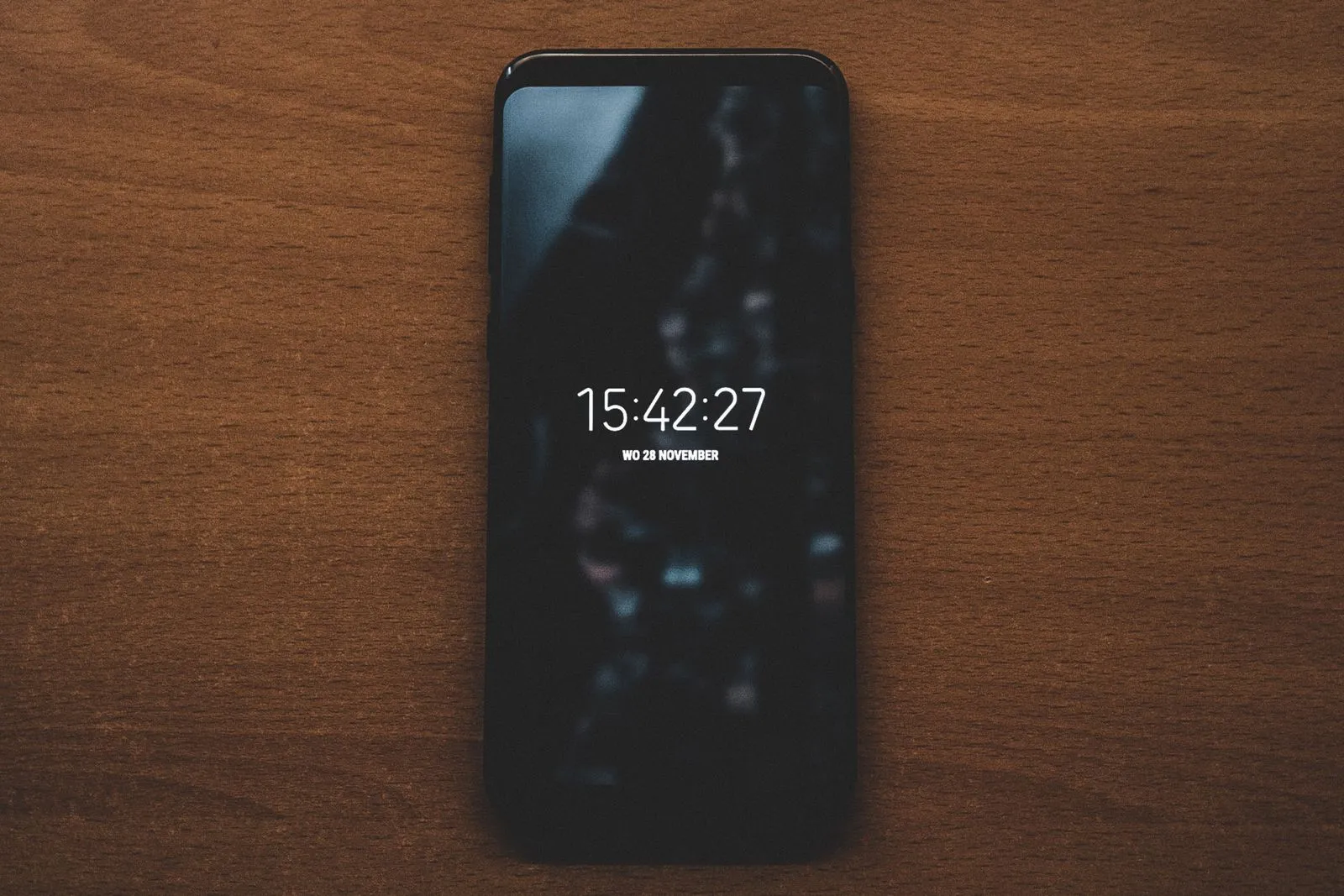 Smartphone appoggiato su un tavolo di legno, sullo schermo l'ora e la data