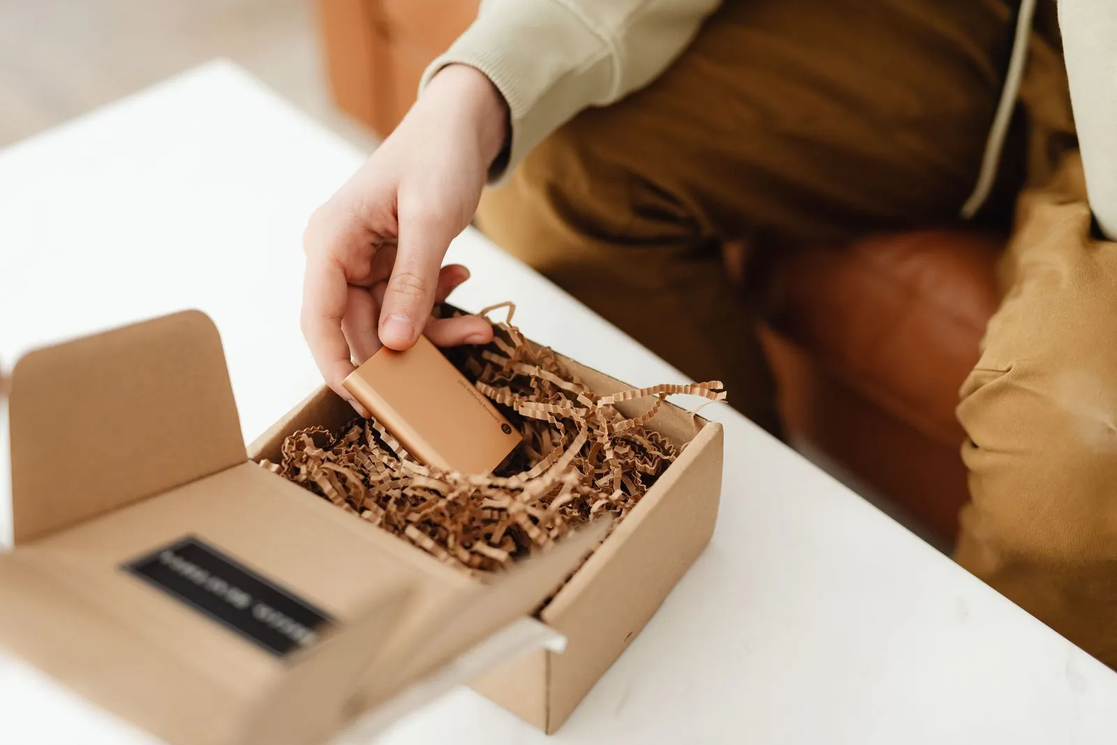 A hand takes a small device out of a shipping box filled with paper padding